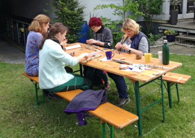Pädagogische Akademie Ute Jenkel, Fachkräfte am Tisch im Garten gestalten Kreatives
